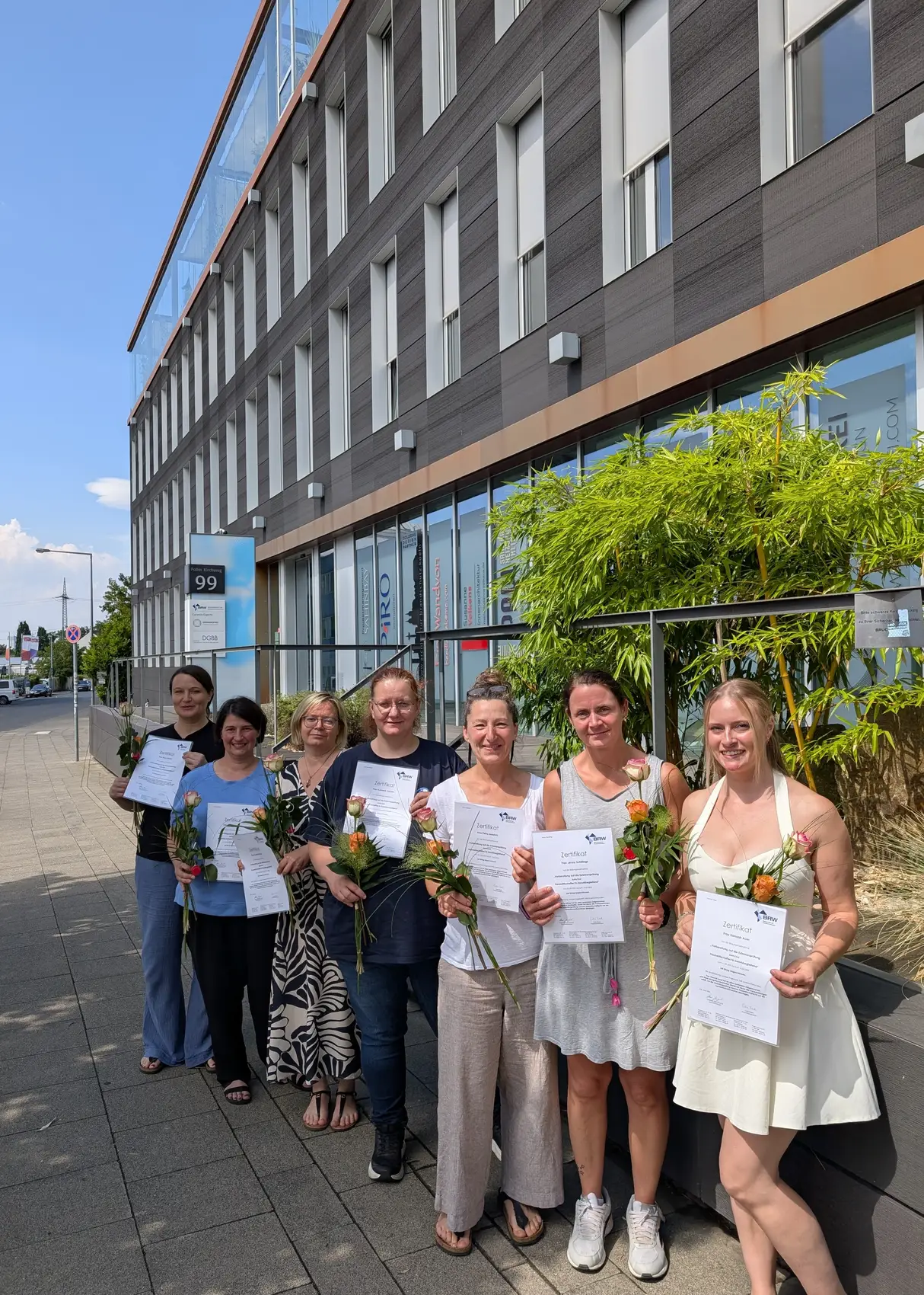 Absolventinnen des Hauswirtschaftskurses mit Zertifikaten und Rosen vor dem BRW-Gebäude am Poller Kirchweg