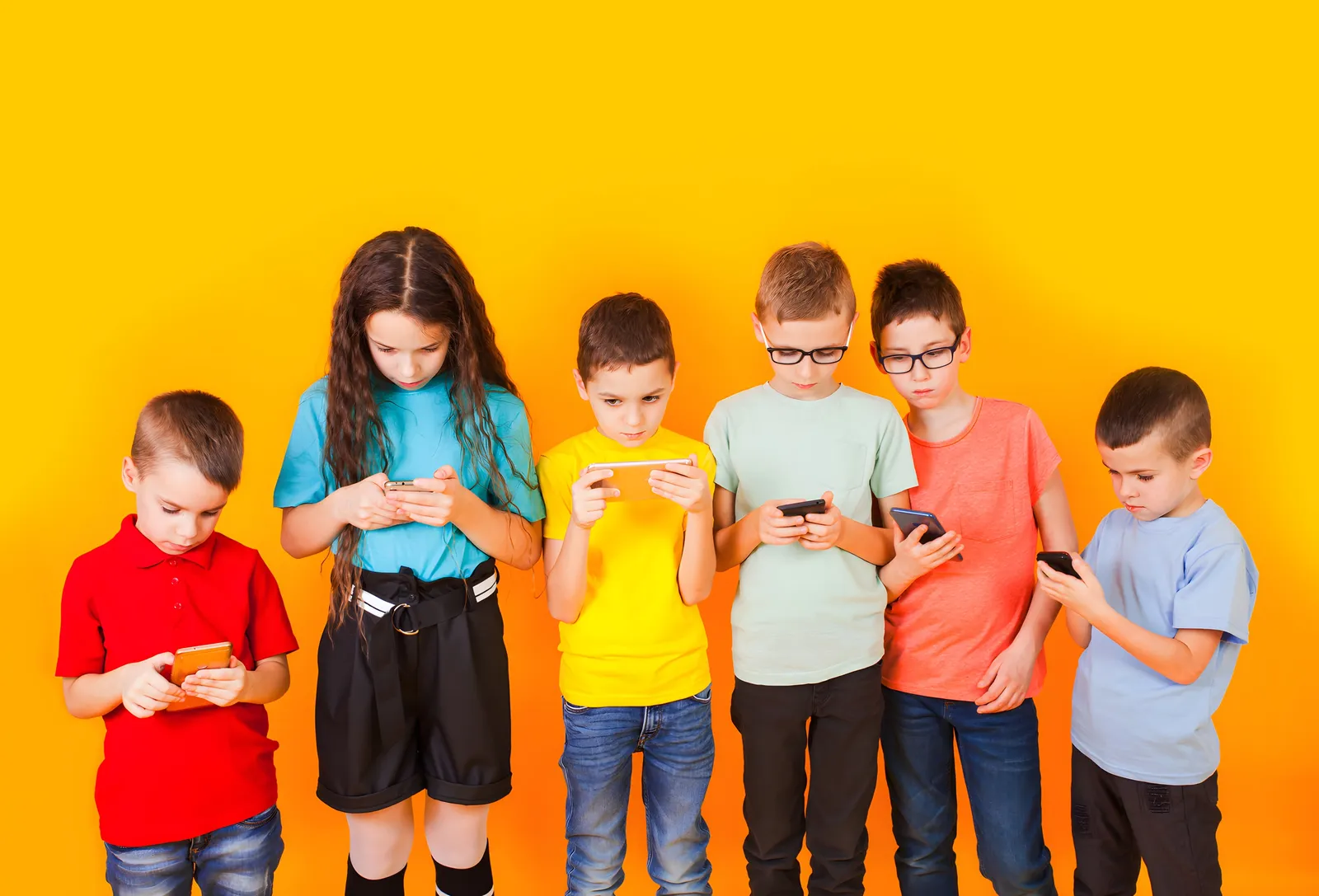 Kinder stehen nebeneinander und schauen auf ihre Smartphones