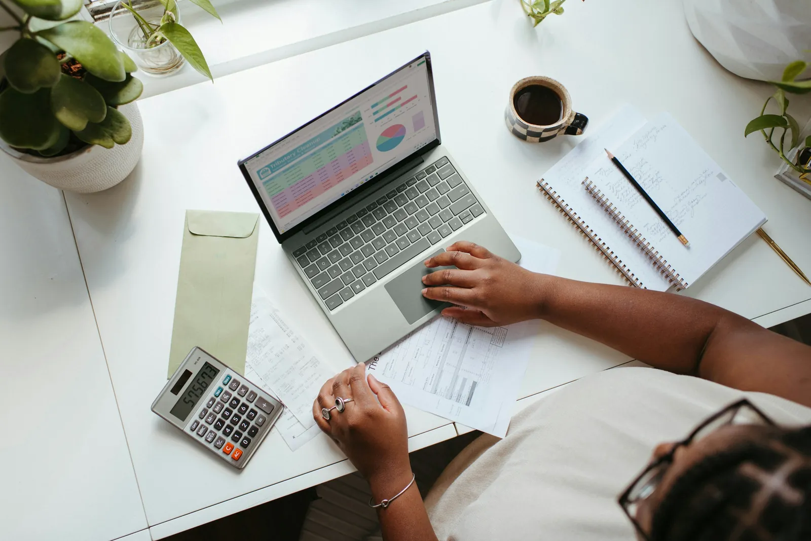 Laptop mit Excel-Diagrammen, daneben Taschenrechner und Unterlagen